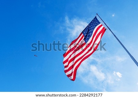American Flag blowing in the wind with a blue sky background. USA American Flag. Waving United states of America famous flag in front of blue sky. Independence Day. Elections Day