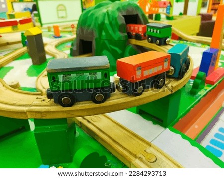Green, white, orange, blue, red, yellow wooden train toy going up the hill, crossing the bridge, passing the train station, and also going through the tunnel. Close up of wooden toy railway with train