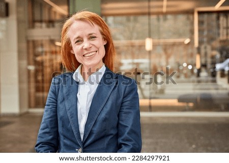 Successful middle-aged businesswoman smiling in front of luxury office.