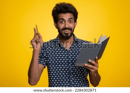 Thoughtful journalist indian man making notes, writing down thoughts with pen into notepad notebook diary, to do list, good idea. Handsome bearded hindu guy isolated alone on yellow studio background Royalty-Free Stock Photo #2284302871