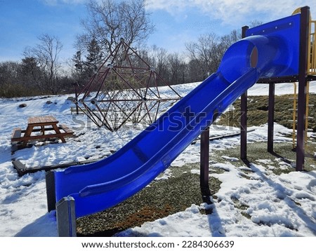 A blue slide at a playground on a winter day.