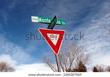 Yield Sign on city street with clouds and blue sky behind it