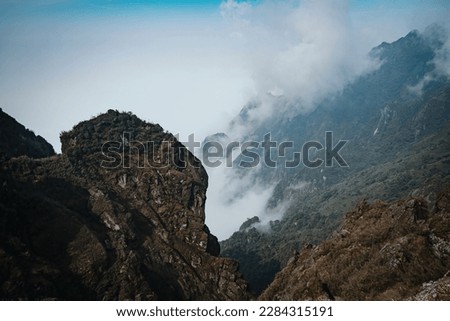 The view from top of Fansipan mountain in Sapa Hoang Lien Son mountain range, Rocky mountain peaks emerge through the misty clouds at Lao Cai. Scenic aerial view. Fly over clouds or fog.