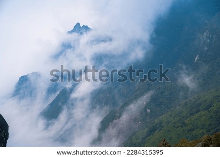The view from top of Fansipan mountain in Sapa Hoang Lien Son mountain range, Rocky mountain peaks emerge through the misty clouds at Lao Cai. Scenic aerial view. Fly over clouds or fog.
