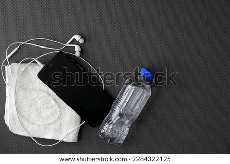 Mat to exercise with the necessary objects such as wireless headphones, cell phone, water to hydrate, sweat towel and locker keys Royalty-Free Stock Photo #2284322125
