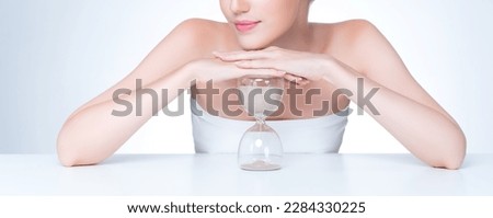 Closeup personable model holding hourglass in beauty concept of anti-aging skincare treatment. Young girl portrait with perfect smooth clean skin and flawless soft makeup in isolated background Royalty-Free Stock Photo #2284330225