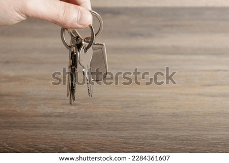 Man holding a bunch of keys in his hand on a wooden background