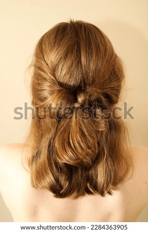 Young woman with mid-length dark blonde hair in a half-up hairstyle. Twisted half-up ponytail. Hairstyle. Casual hairstyle. Bare shoulders. Back view of a hairstyle. No face. 