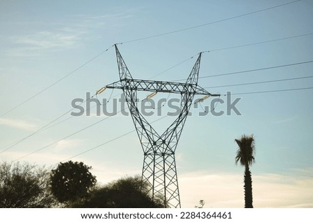 High voltage electricity tower placed in a park near the city during sunset. Concept energy, electricity, towers, high voltage.