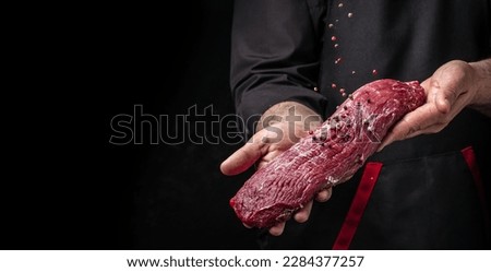 Chef salts steak in a freeze motion with rosemary and spices. Preparing fresh beef or pork on a dark background. Long banner format. Royalty-Free Stock Photo #2284377257