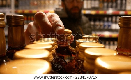 Close-up of glass bottles with liquor or cognac and a male buyer takes one
