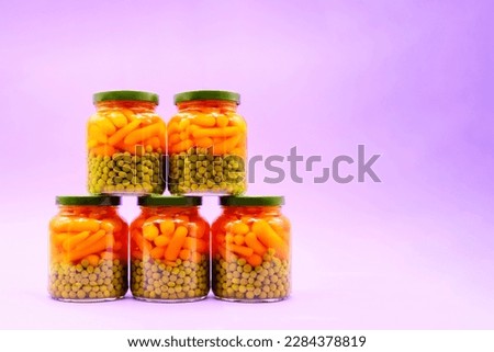 Green peas and carrots, canned in a glass jar. 100% natural product, close-up, side view, empty space for text, magenta background