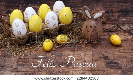 Happy Easter greeting card: Yellow and white Easter eggs in an egg box with an Easter greeting. Spanish inscription means Happy Easter.