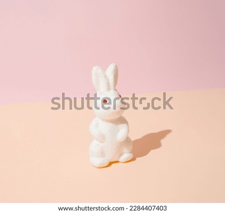 White Easter bunny on a light yellow and pink pastel background.