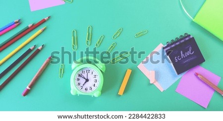 Alarm clock, Art materials and stationery on a green background, top view, back to school, holidays, education and training