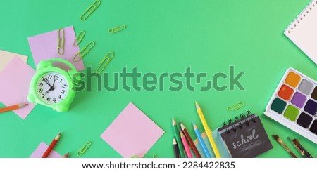 Alarm clock, Art materials and stationery on a green background, top view, back to school, holidays, education and training