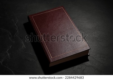One old hardcover book on black textured table Royalty-Free Stock Photo #2284429683