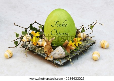 Nest with Easter bunnies, Easter eggs and an inscribed Easter egg. German inscription means Happy Easter.