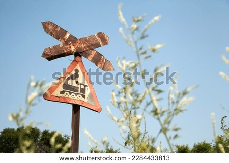Very old rusty road sign with a train picture - railroad crossing. Red weathered triangle traffic sign against the sky
