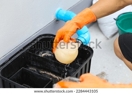 A man cleaning a grease traps box outside the house, water treatment.  Royalty-Free Stock Photo #2284443105