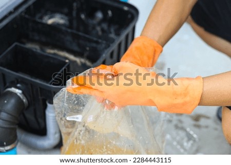 A man cleaning a grease traps box outside the house, water treatment.  Royalty-Free Stock Photo #2284443115