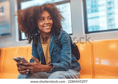 Happy young African American woman passenger smile and using smart mobile phone in subway train station Royalty-Free Stock Photo #2284445297