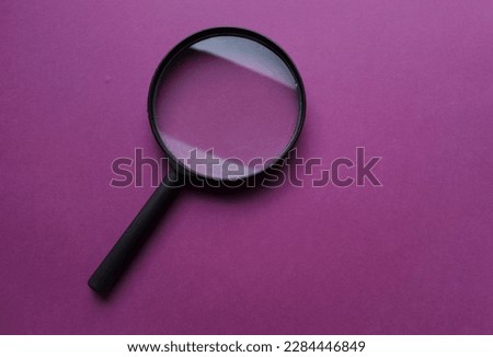black frame a magnifying glass on Rectangle shape colored paper white and purple background