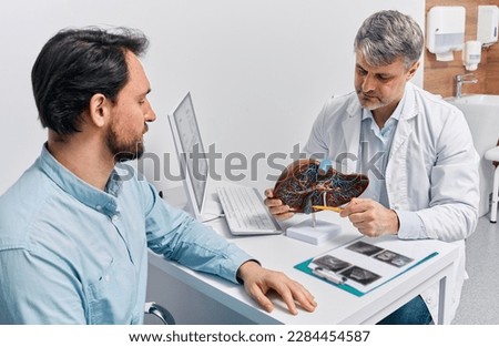 Gastroenterologist doctor explaining liver and gallbladder problems using anatomical model to patient during clinic visit. Treatment of gallbladder and liver diseases Royalty-Free Stock Photo #2284454587