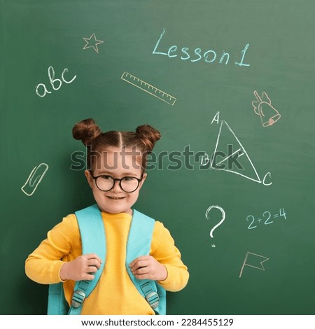 School girl near green chalkboard with drawings and inscriptions