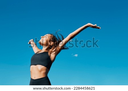 Horizontal portrait of a beautiful young fit smiling woman deep breathing in front of a clear blue sky in a sunny windy day of summer Royalty-Free Stock Photo #2284458621