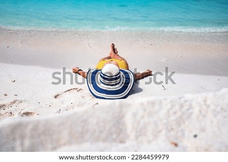 woman with straw hat sunbathing on tropical beach