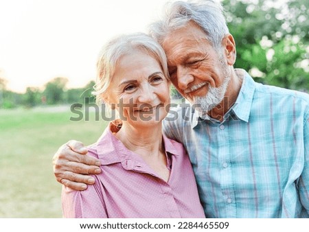 Happy active senior couple walking daydreaming thinking and relaxing and hugging in park outdoors Royalty-Free Stock Photo #2284465509