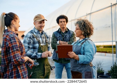 Greenhouse owner using digital tablet while having a meeting with her workers.