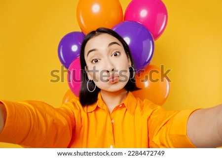 Close up happy fun young woman wear casual clothes celebrating near balloons doing duckface selfie shot pov mobile cell phone isolated on plain yellow background Birthday 8 14 holiday party concept