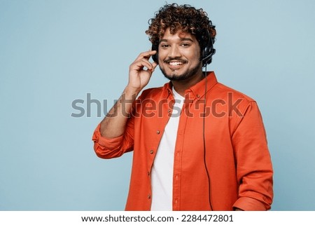 Young employee operator Indian business man in set microphone headset for helpline assistance wears orange red shirt white t-shirt work at call center isolated on plain pastel light blue background Royalty-Free Stock Photo #2284472801