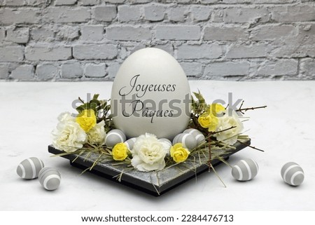 Happy Easter greeting card: Inscribed Easter egg with flowers and branches. French inscription means Happy Easter.