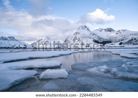 The bay, surrounded by snowy mountains and dotted with ice formations. The magic of nature in its frozen splendor. Unique juxtaposition of ice and sea Royalty-Free Stock Photo #2284485549