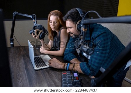 Two people sitting at the table and watching something on laptop