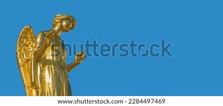 Banner with beautiful golden angel statue with blue sky solid background with copy space.