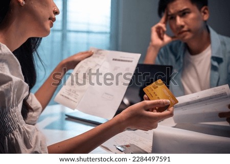 Asian young depressed couple having argument while checking money debt. Attractive new marriage man and woman looking frustrated to paperwork and bill, feel worried about financial problem in house. Royalty-Free Stock Photo #2284497591