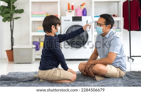 Portrait of happy love asian family mature father and little boy son wearing protective mask with social distancing use infrared forehead thermometer for checking body temperature scan fever, sick Royalty-Free Stock Photo #2284506679
