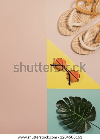summer vacation concept, travel background with copy space. beach accessories sunglasses, straw flip flop, tropical leaves on geometrical colorful background, flat lay, top view.