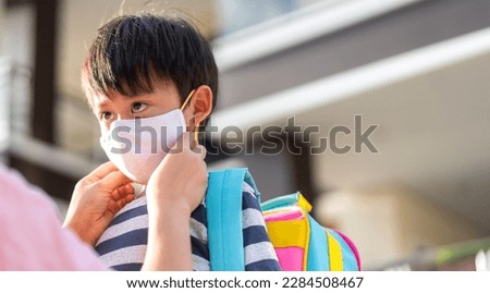 Portrait of enjoy love asian mother wearing protective safety mask for little boy son in quarantine for coronavirus with social distancing go back to school after covid-19 with backpack.Back to school Royalty-Free Stock Photo #2284508467