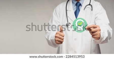 Doctor holding a quality assurance symbol while standing in the hospital. Quality assurance concept. Space for text. Close-up photo