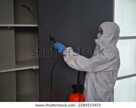 Person in protective suit and mask disinfects closet at home. volumetric disinfection of premises and services to get rid of rodents and viruses