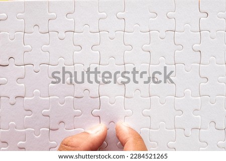 Flat lay top view photo of Hand assemble last piece white jigsaw or puzzle use for Success,finish,goal,business concept.