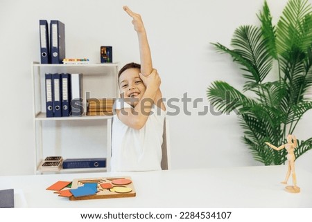a boy reaches out his hand at a table with an educational game in the office