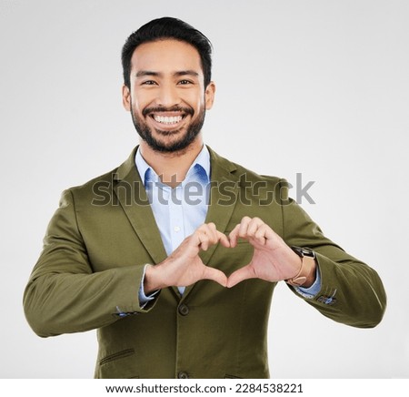 Portrait, heart and hand gesture with a business man in studio on a gray background for health or love. Hands, emoji and shape with a happy male employee showing a symbol or sign of affection