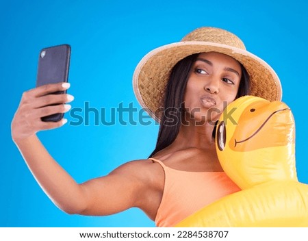 Happy woman, selfie and swimming vacation for social media or profile picture with inflatable duck against a blue studio background. Excited female model in summer swimwear for photo, travel or trip