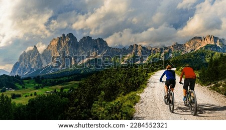 A man and woman ride electric mountain bikes in the Dolomites in Italy. Mountain biking adventure on beautiful mountain trails. Royalty-Free Stock Photo #2284552321